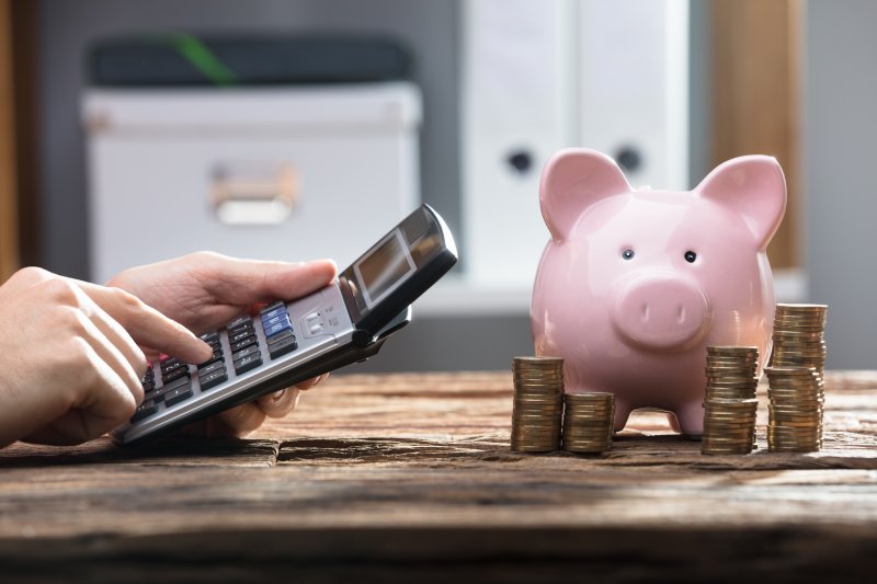 Person operates calculator by piggy bank