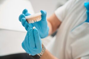 Dentist holding crown up to model of mouth. 